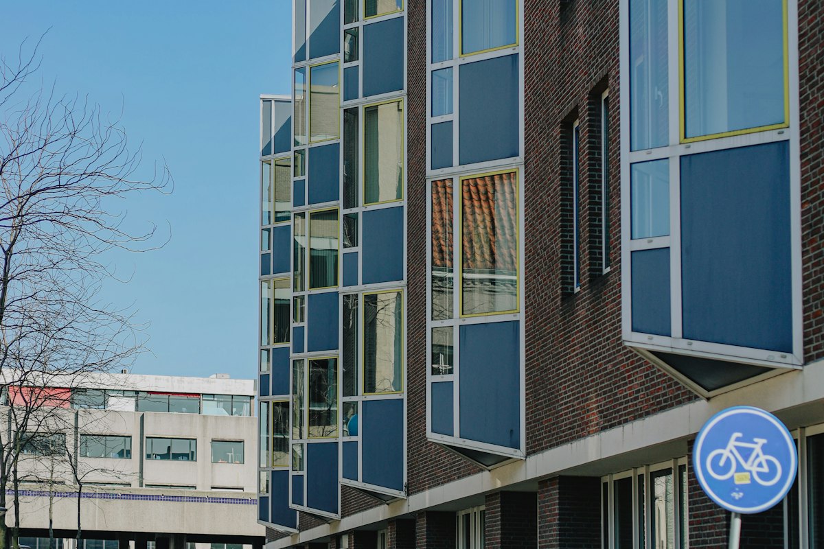 Moderne gevel van een nieuwbouwflat met blauwe erkers en baksteen