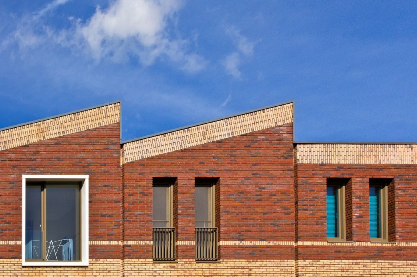 Moderne bakstenen nieuwbouwgevel onder een blauwe lucht