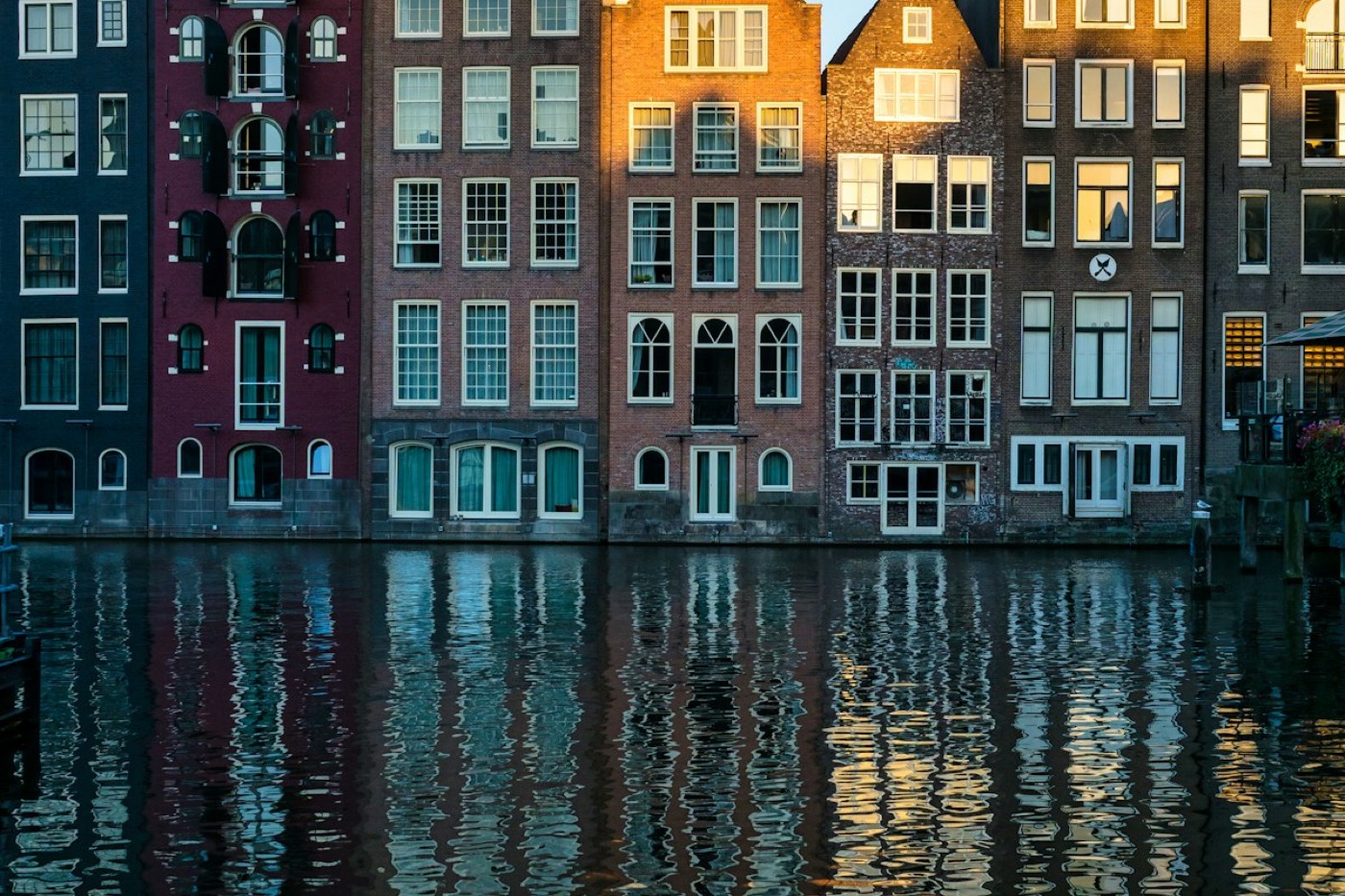 Grachtenhuizen in Amsterdam die weerspiegelen in het water bij avondlicht